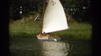 CAPE COD MASSACHUSETTS-1956: Several People On A Sailboat Going Past A Grassy