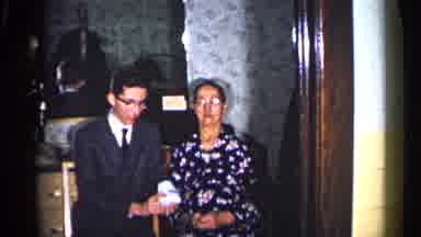 Duluth Minnesota-1960: Young Man In Suit Shows Object To Older Woman In Living Room