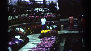 Minnesota USA (1964): A Lady Walking In The Park With Different Flowers On Both