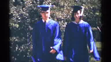 Minnesota USA (1964): Two People In Cap And Gown Walking Towards Camera
