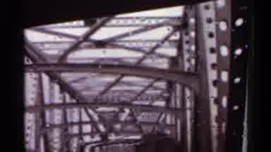 Arkansas USA (1965): Car Driving Along Underneath A Big Metal Bridge With A Car In