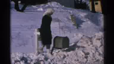 Minnesota USA (1965): A Woman Sits On Her Mailbox Because The Snow Is Piled Up To