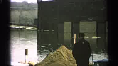 Minnesota USA (1965): A Man In A Jacket And Hat Walks Through A Flooded City