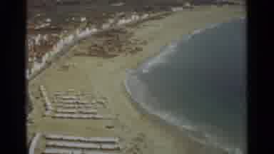 NAZARE PORTUGAL-1965: An Aerial View Shows Wave Rolling Into A Beach With Umbrellas