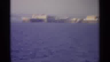 Sicily-1965: Grainy Vintage Film Recording Depicting Coastal Cityscape Across Blue Bay