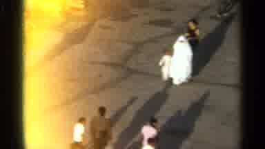 TANGIER MOROCCO-1965: Woman In White Hijab And Child Walking Through Market Street