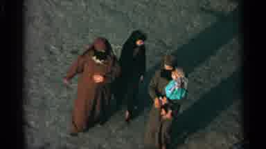 TANGIER MOROCCO-1965: Three Hooded Women Walking With A Child In A Desert