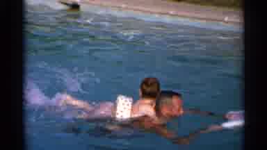 US Virgin Islands (1966): A Man Swimming In A Pool With A Child Holding Onto His
