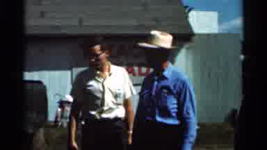Wauseon Ohio (1966): Man Wearing White Shirt Stands In Front Of Red And White Sign