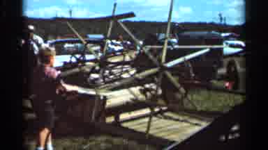 Wauseon Ohio (1966): A Child Spins An Industrial Wheel And Adults Look At Outdoor