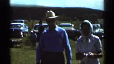 Wauseon Ohio (1966): An Older Couple Walks In Front Of Parked Cars Followed By A