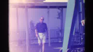 US Virgin Islands (1967): A Man Walking Outside Pass Some Carnival Rides Along