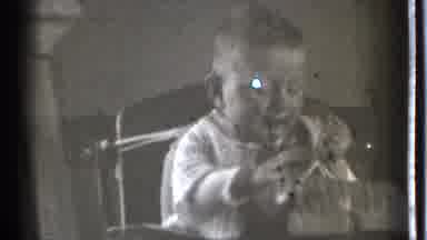 Danielson Connecticut (1939): Baby Wearing White Sweater Looks At Object While
