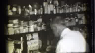 Danielson Connecticut (1939): Man Wearing White Shirt Stands In Front Of Shelves