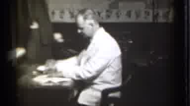 Danielson Connecticut (1939): Man Signs Pieces Of Paper While Sitting In Chair At