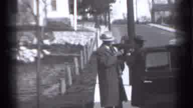 New York (1939): Man Wearing Grey Cot Holds Toddler While Woman Unloads Black Car