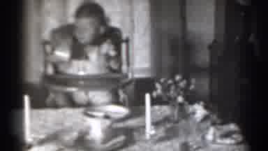 New York (1939): Baby In High Chair Examining Cup At Table With Plates And Candles