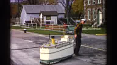 Michigan USA (1960): Man In Military Uniformity Pulling Boat Model And Ocean