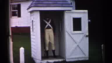 Michigan USA (1960): Person Wearing Tn Ants Stands Inside White Shed On Cleo Day