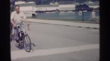 Michigan USA (1960): Two Men Riding Silver Bicycles On Bright Sunny Day