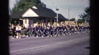 Minnesota USA (1961): Band Wearing Blue And Grey Uniforms Walk Past White Building