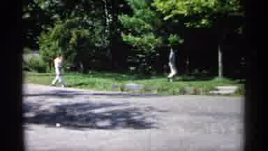 Minnesota USA (1961): Two People Walk On Green Grass On Bright Sunny Day