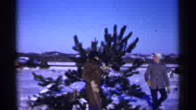 Minnesota USA (1961): Two Men One With Tree In One Hand And Saw In Other Snow