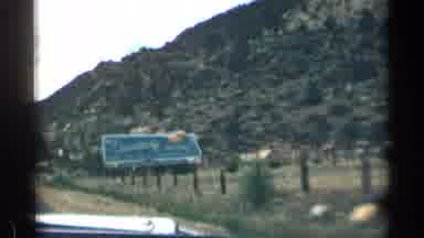 Colorado USA (1963): Car Drives By Two Signs And Shows Landscape Round M