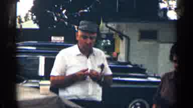 Texas USA (1963): Man And Woman Sand In Parking Lot Eating And Talking One Irked