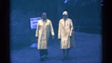 Niagra Falls Canada (1964): Two People Walk Towards Comer Wearing Yellow Raincoats