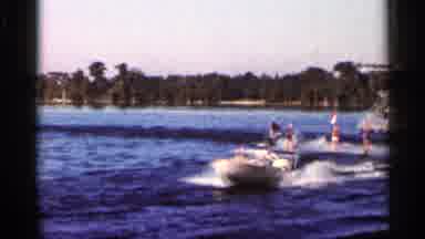 Florida USA (1966): Three Water Skiers Carrying Flags Follow Behind Speedboat On