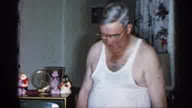 New York-1955: Elderly Couple Play With Child Riding Rolling Toy In Living Room