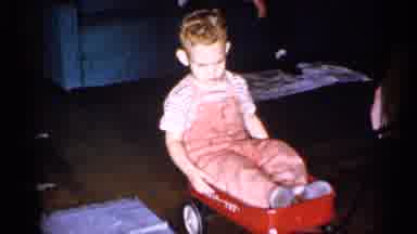 New York (1955): Young Child Wearing Jumper Riding On Small Red Wong Being Pulled