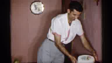 New York (1955): Smiling Man Sets Cake Down On Table Barefoot Joining His Family