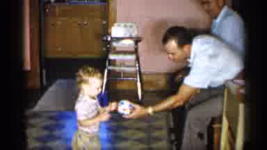 New York (1955): Male Family Members Passing Ball To Young Toddler And Family