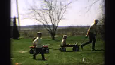 Arizona (1959): Man Wearing White Shirt Pulls Two Kids Sitting In Red Wagons