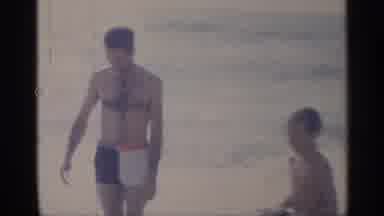 California (1959): Man Wearing White Shirt Pulls Woman Wearing Blue Swimwear