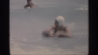 California (1959): Man And Woman Swim In Ocean On Lots Other Swimmers Are Derby