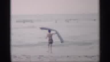California (1959): Little Boy With Black Shooter Is Putting Lots In Sea To Surf On
