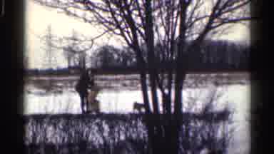 California-1959: Two Black Dogs Running Round Curve In Snowy Field Towards Man
