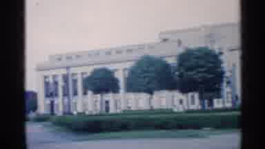 Indiana (1959): Cars Are Parked Alongside Of Large Historic Building With