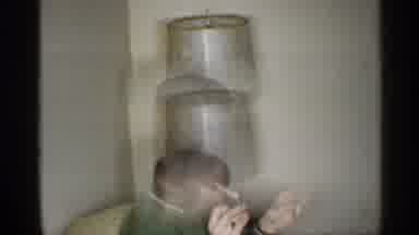 Indiana (1959): Man In Living Room Sits On Couch And Lights Cigarette With Mitch