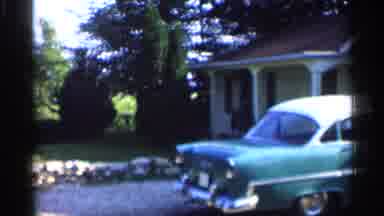 Indiana (1959): Blue Car Irked Next To Yellow House On Sunny Day