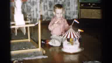 Michigan (1959): Boy Wearing Pink Shirt Plays With Red And White Object On Brown