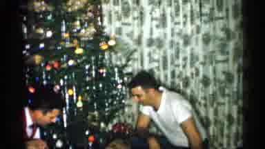 Michigan (1959): Two People Sitting And Smiling With Child Opening Present One