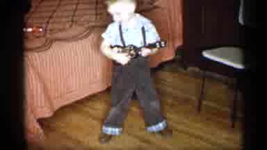 Michigan (1959): Boy Wearing Brown Pants Holds Small Brown Toy Guitar While Man