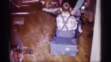 Michigan (1959): Kid Playing The Toy Car While A Woman Chills On A Sofa