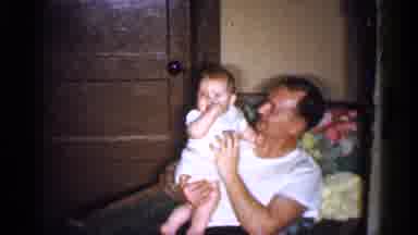 Michigan (1959): Man Wearing White Shirt Holds And Tickles Baby Wearing White