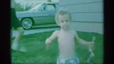 New York (1959): Child In Shorts Runs Toward Camera Outside On Lawn Holding Shovel