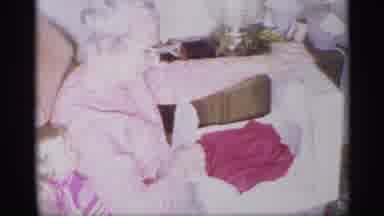 New York (1959): Older Woman Sitting On A Couch Happily Unwrapping A Red Shirt She